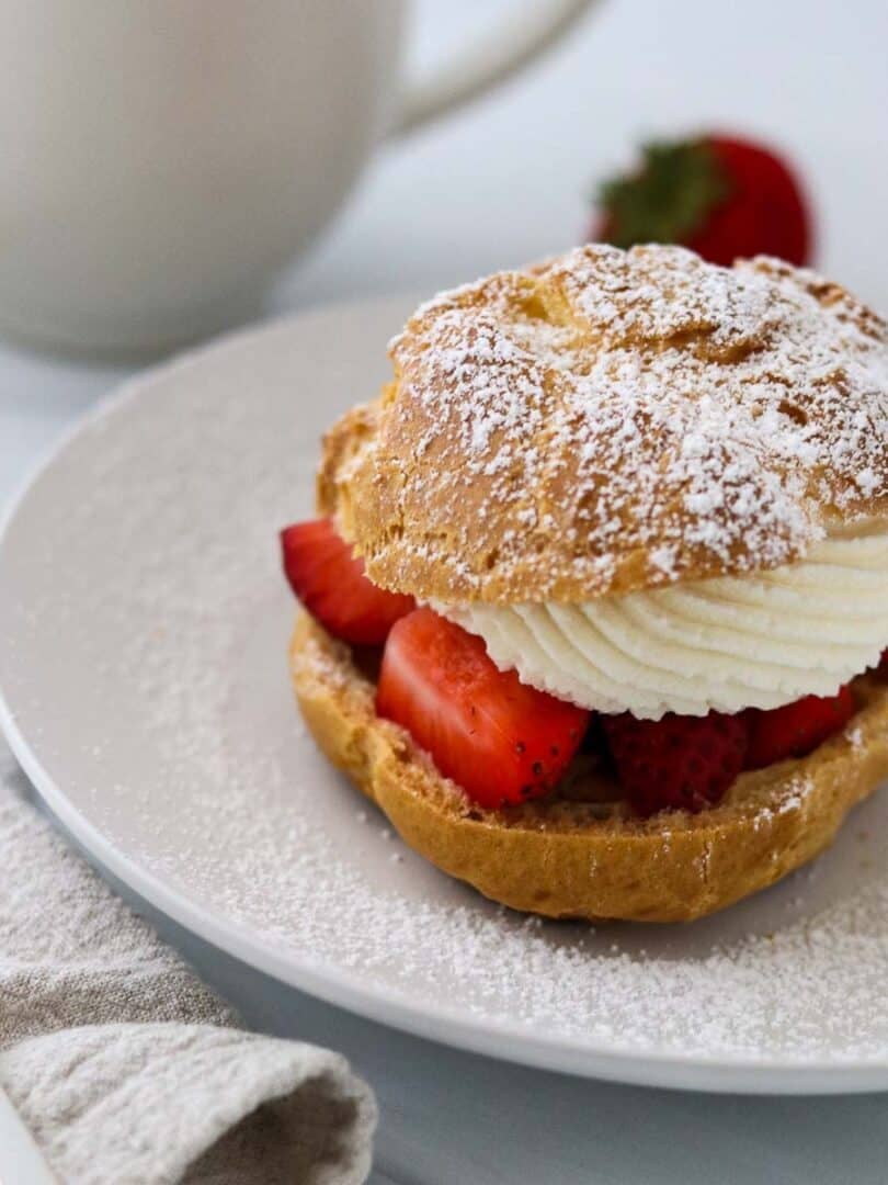 Cream puff filled with strawberries and whipped cream and sprinkled with powdered sugar.