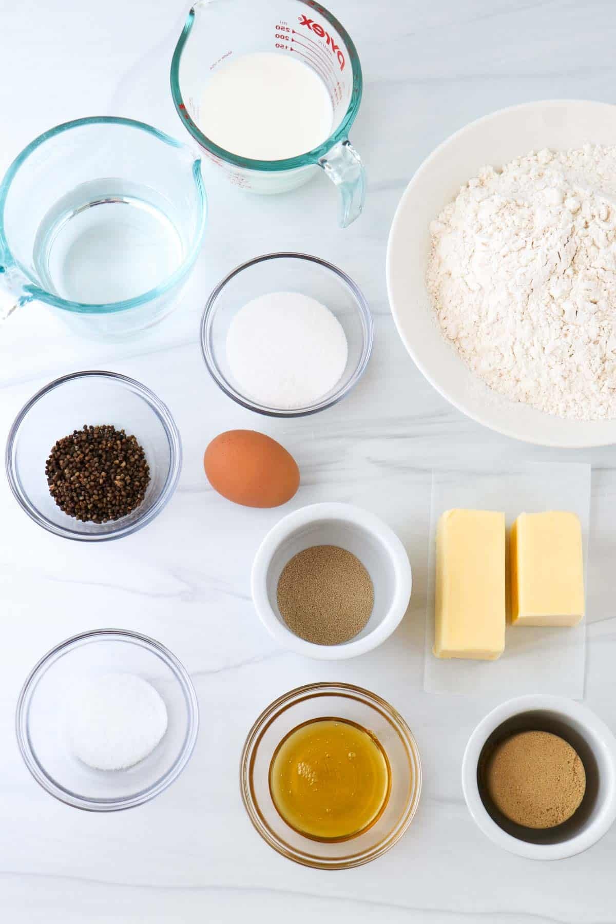 Ingredients needed for making Swedish Cardamom Buns (Kardemummabullar): Flour, yeast, milk, egg, water, sugar, brown sugar, cardamom, butter, brown sugar, golden syrup, salt.