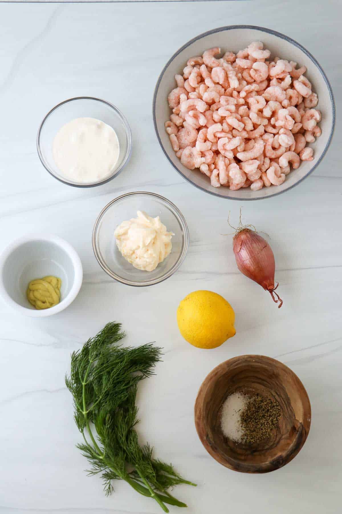 Ingredients needed to make Skagenröra: frozen shrimp, mayonnaise, creme fraiche, shallot, mustard, lemon, salt and pepper and fresh dill.