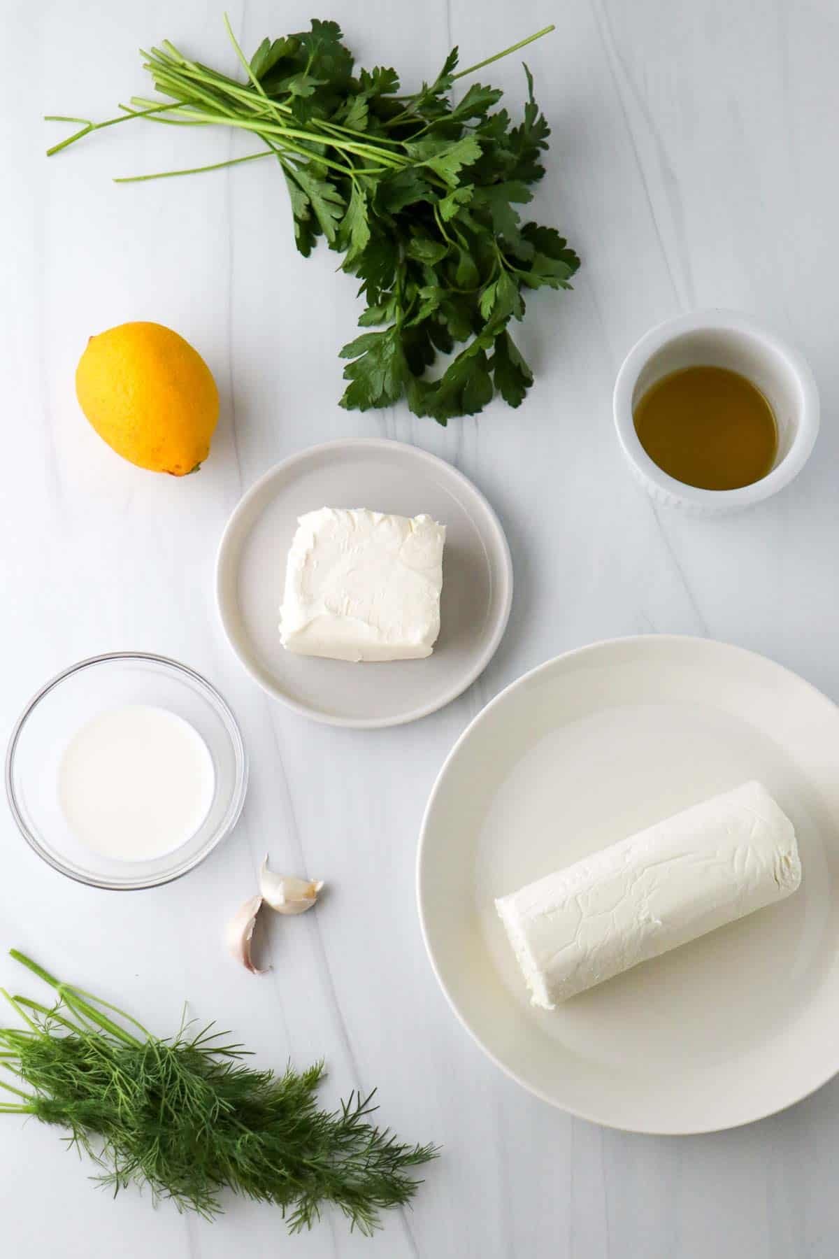 Ingredients for making Easy Herbed Whipped Goat Cheese: Goat cheese, cream cheese, milk, garlic, lemon, olive oil, parsley and dill.