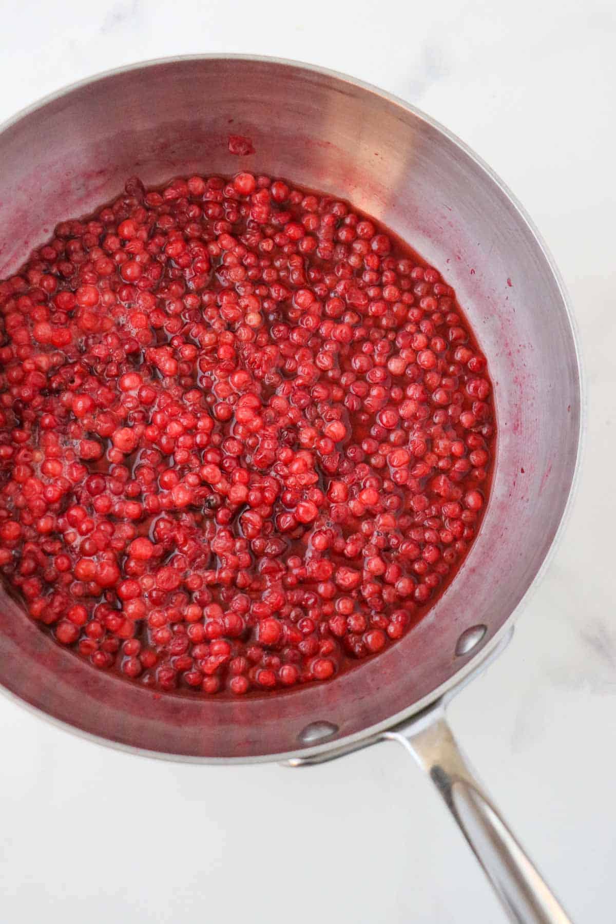 Lingonberries and sugar in a saucepan.